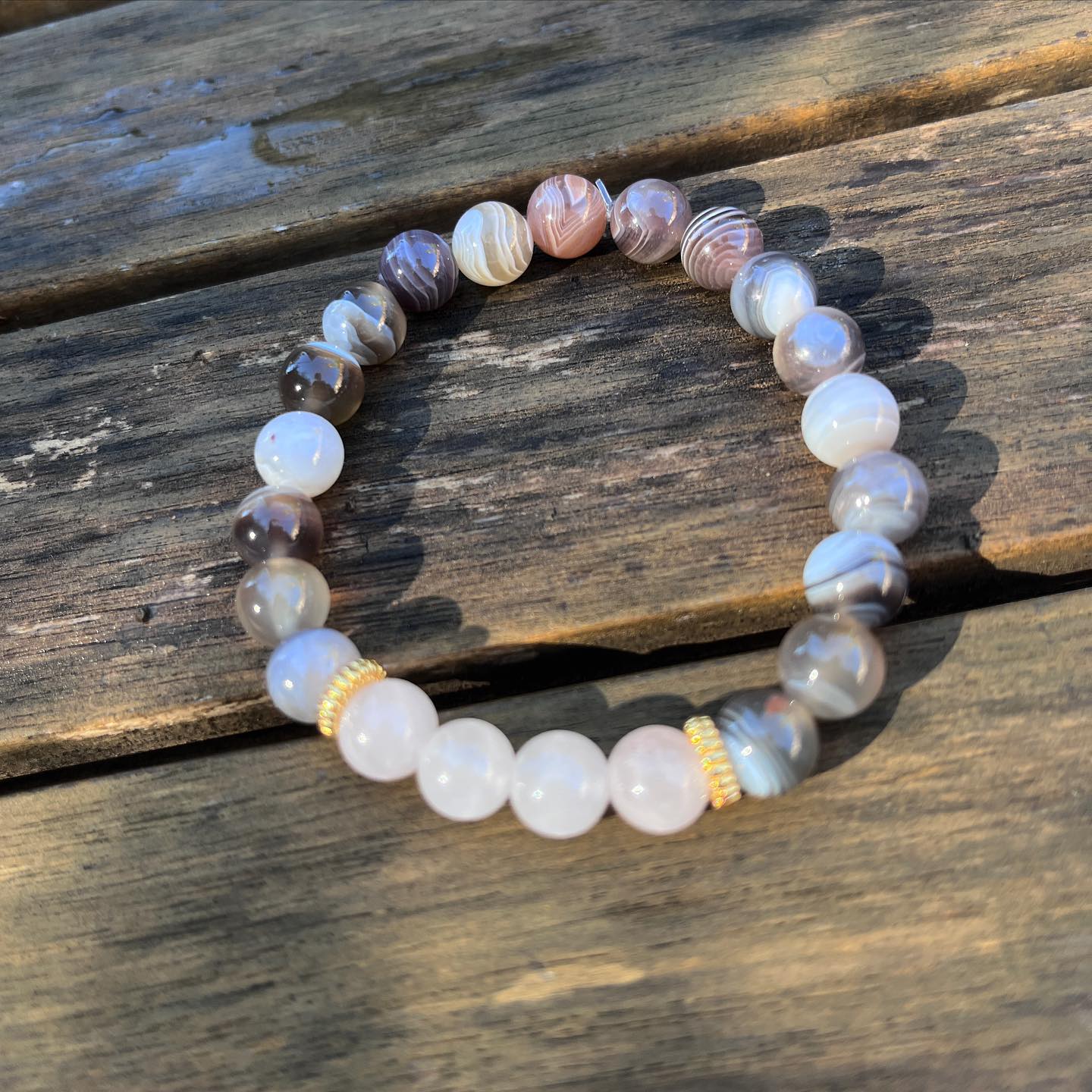 bracelet en pierre naturelles d'agate de botswana, de quartz rose posé sur une table en bois