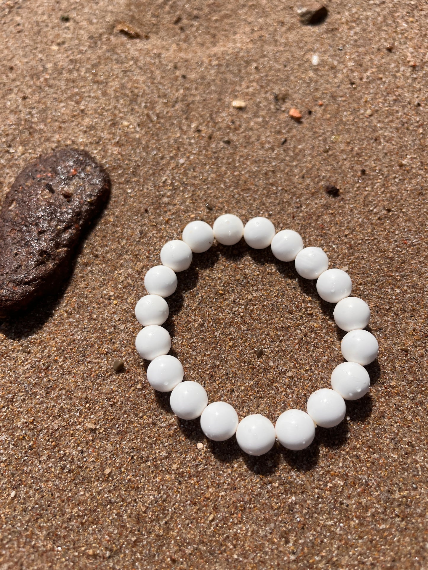 bracelet en perles de coquillages de bénitier posé sur du sable