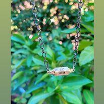 collier chaîne noire ras de cou et pendentif doré portant l'inscription Lucky